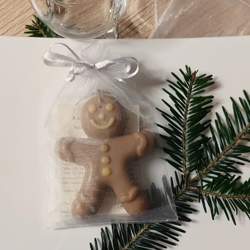 Savon en forme de bonhomme en pain d'épices dans son sachet en organza présenté à table comme cadeau invité